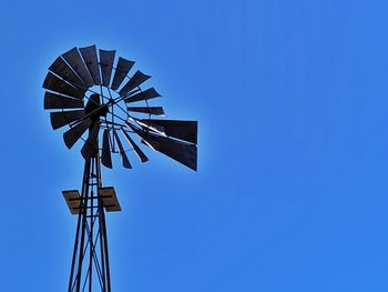 Low angle view of windmill against clear blue sky