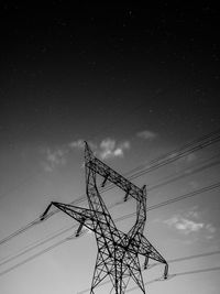 Low angle view of electricity pylon against sky at night