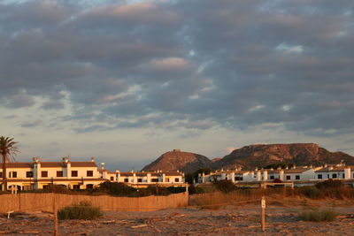 Houses by buildings in city against sky