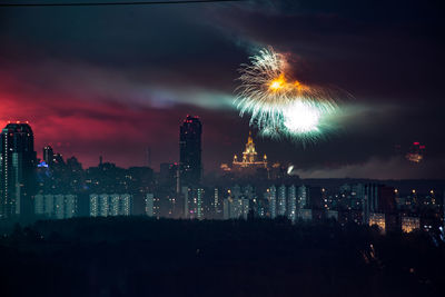 Firework display over illuminated buildings in city at night