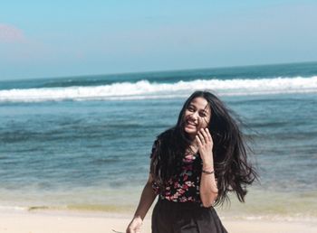 Portrait of smiling woman standing on beach