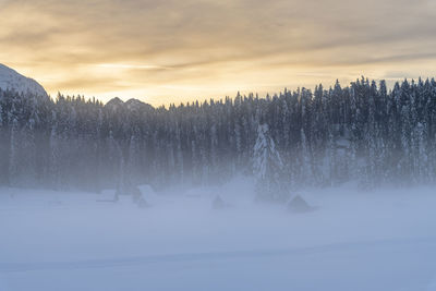 Scenic view of snow covered land against sky during sunset