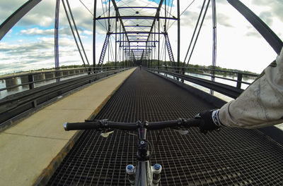 Close-up of man riding bicycle on bridge against sky