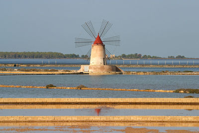 Traditional windmill by salt basin against clear sky