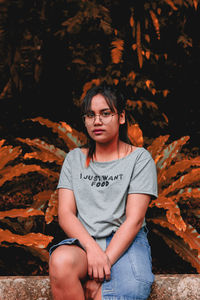 Portrait of beautiful young woman sitting on rock