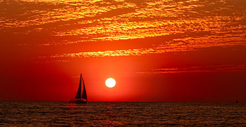 Sailboat sailing on sea during sunset