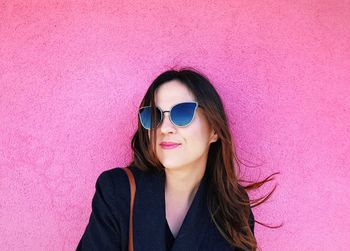 Portrait of woman wearing sunglasses against pink wall