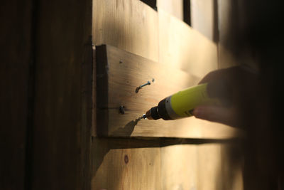 Cropped hand drilling wooden wall