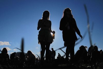 Low angle view of silhouette people standing against clear sky
