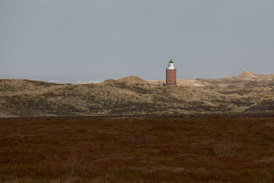 Lighthouse on field against sky