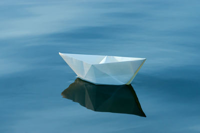 Close-up of paper floating on water against blue sky