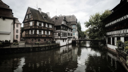 Buildings by river against sky in city