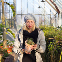 Beautiful young woman standing against plants