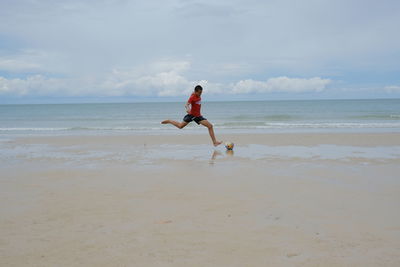 Full length of man playing on beach against sky