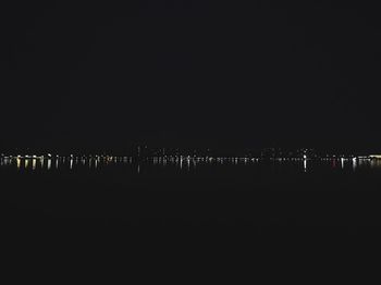 Illuminated sea against clear sky at night