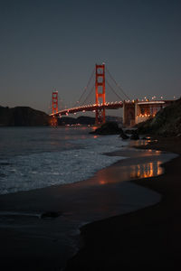 Illuminated bridge over river at night