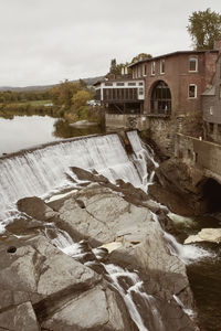 River flowing by building against sky