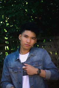 Portrait of young man standing against tree