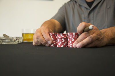 Close-up midsection of man holding gambling chips on table