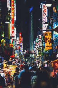 People walking on illuminated street in city at night