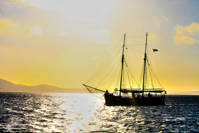 Sailboat sailing in sea against sky during sunset