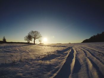 Scenic view of snow field against clear sky during sunset