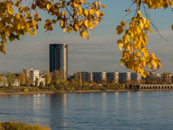 Scenic view of lake by buildings against sky during autumn