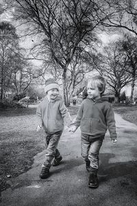 Full length of friends holding hands walking on footpath