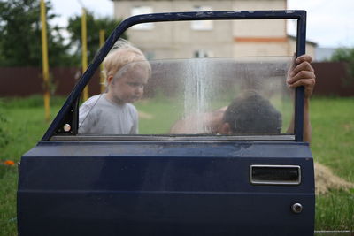 Rear view of father and son repairing a car