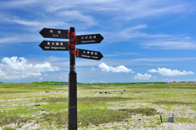 Information sign on field against sky