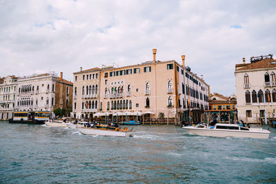 Canal by buildings against sky in city