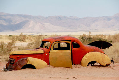 Abandoned car on field against sky