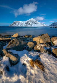 Scenic view of sea and snowcapped mountains against sky