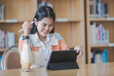 Portrait of woman using phone while sitting on table