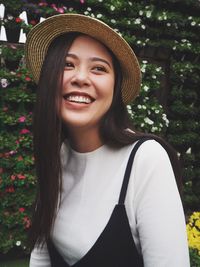 Portrait of smiling young woman standing against trees