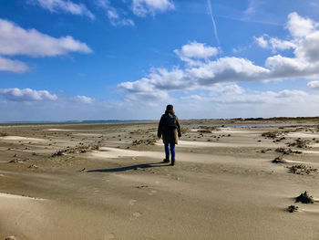 Rear view of man standing on land against sky