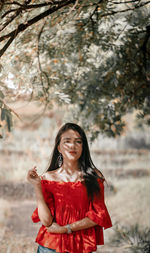 Smiling woman standing against red tree