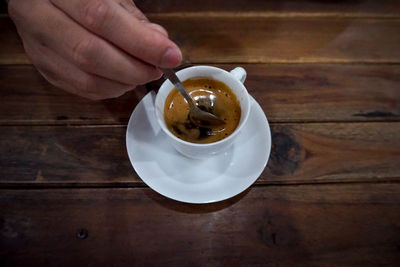 Close-up of hand holding coffee cup on table