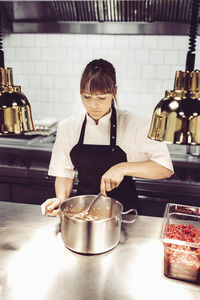 Female chef preparing dish in commercial kitchen