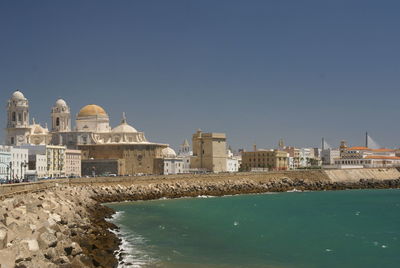 Cadiz cathedral by sea against clear sky