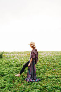 Side view of woman standing on field against clear sky