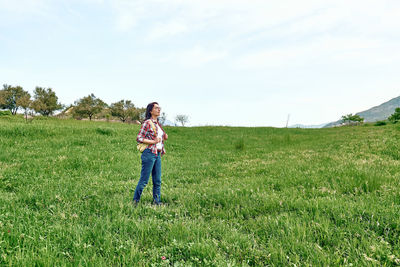 Happy beautiful carefree woman walking on a spring meadow with green grass. hiking outdoors