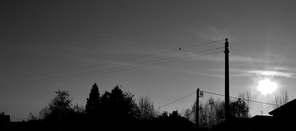 Low angle view of silhouette electricity pylon against sky at sunset