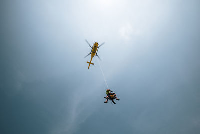 Two paramedics hanging on rope under flying helicopter emergency medical service. 