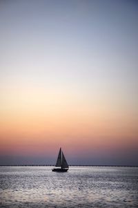 Sailboat sailing on sea against sky during sunset