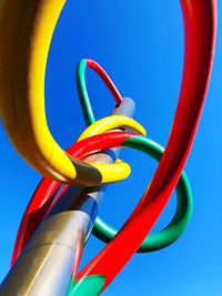 Low angle view of yellow wheel against clear blue sky