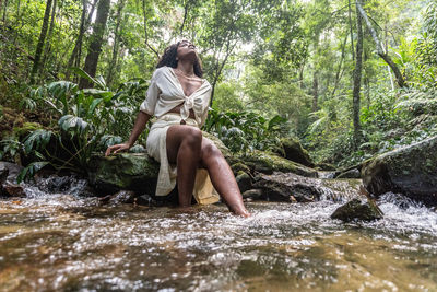 Young woman standing by rocks in forest