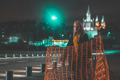 Woman standing at illuminated city at night