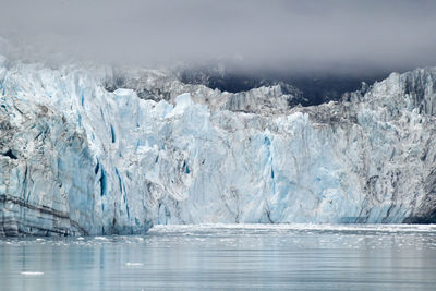 Ancient glacier and foggy dramatic sky in alaska ocean bay