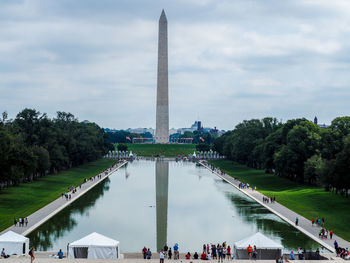 Group of people in front of building against cloudy sky
